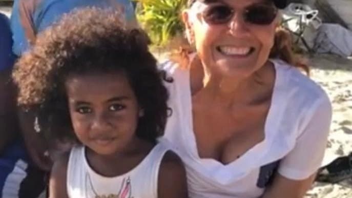 Ofelia Mercedes Méndez, sonriente y con gafas de sol, abrazada a una niña de pelo rizado en una playa