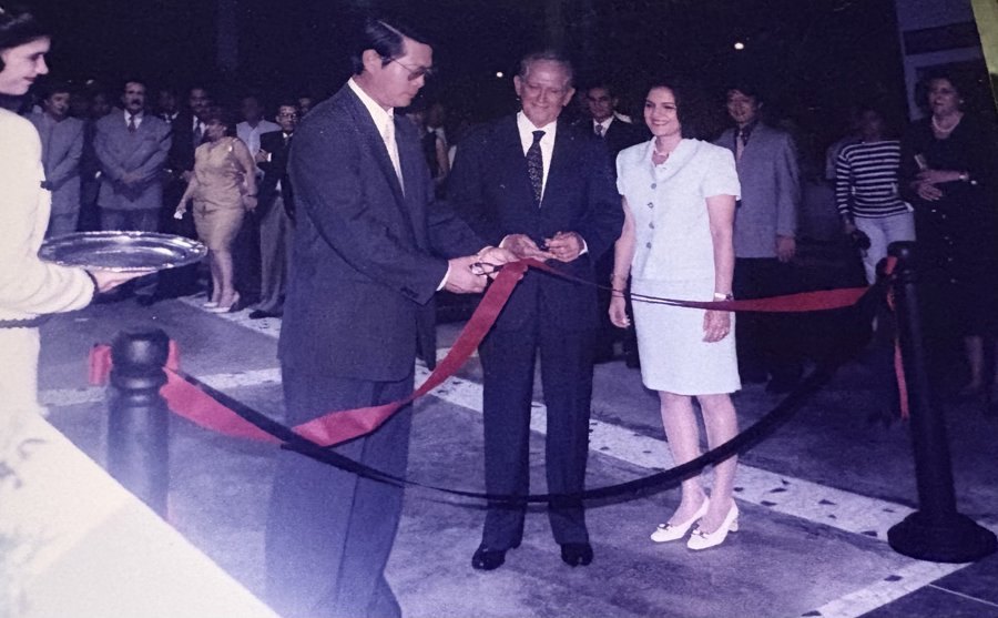 Ofelia Mercedes Méndez, de traje claro, junto a dos hombres que cortan la cinta roja durante la inauguración del concesionario, ante un grupo de invitados