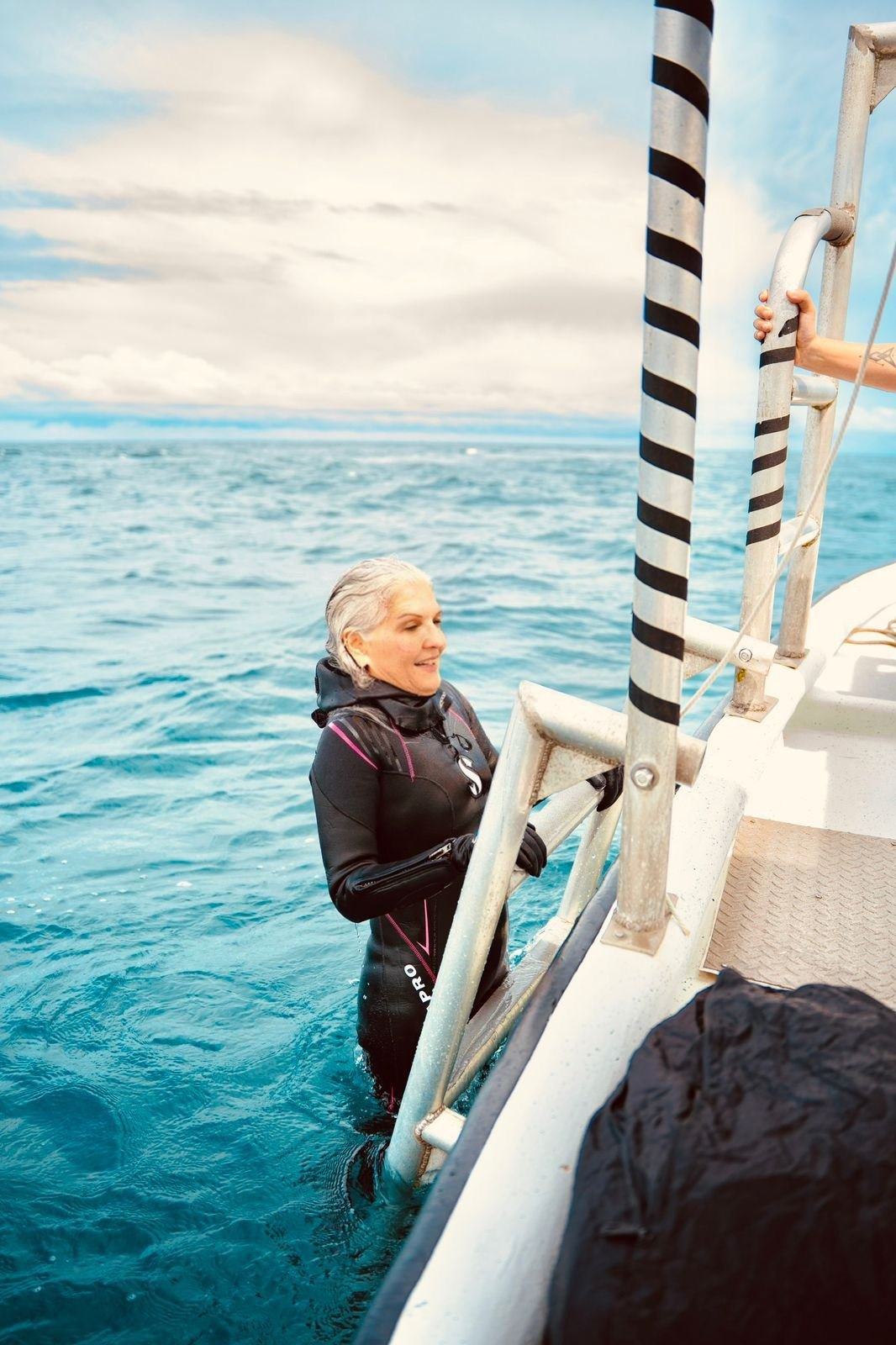 Ofelia Mercedes Méndez, con traje de neopreno, en el agua junto a la escalerilla de un bote, de regreso de una inmersión en mar abierto