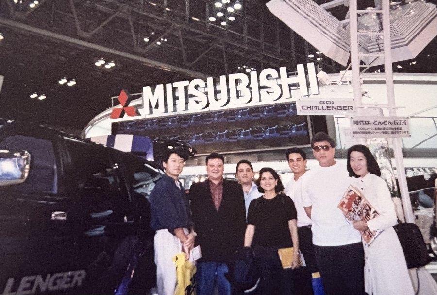 Ofelia Mercedes Méndez con su equipo en el pabellón de una feria internacional de automóviles, junto a un vehículo expuesto bajo el rótulo de una gran marca japonesa